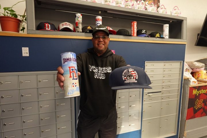 The owner of Yonkers Hub holding local merchandise inside the shop on South Broadway
